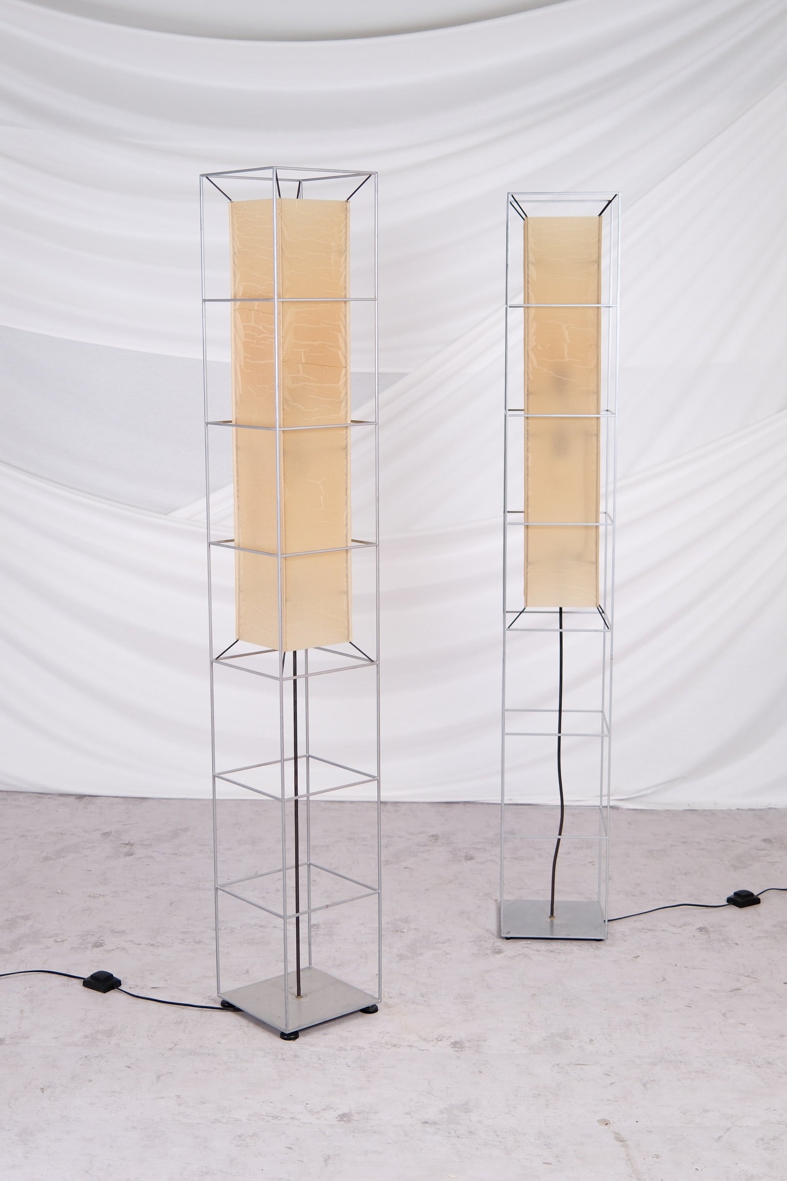 Two modern floor lamps with beige lampshades on a white background