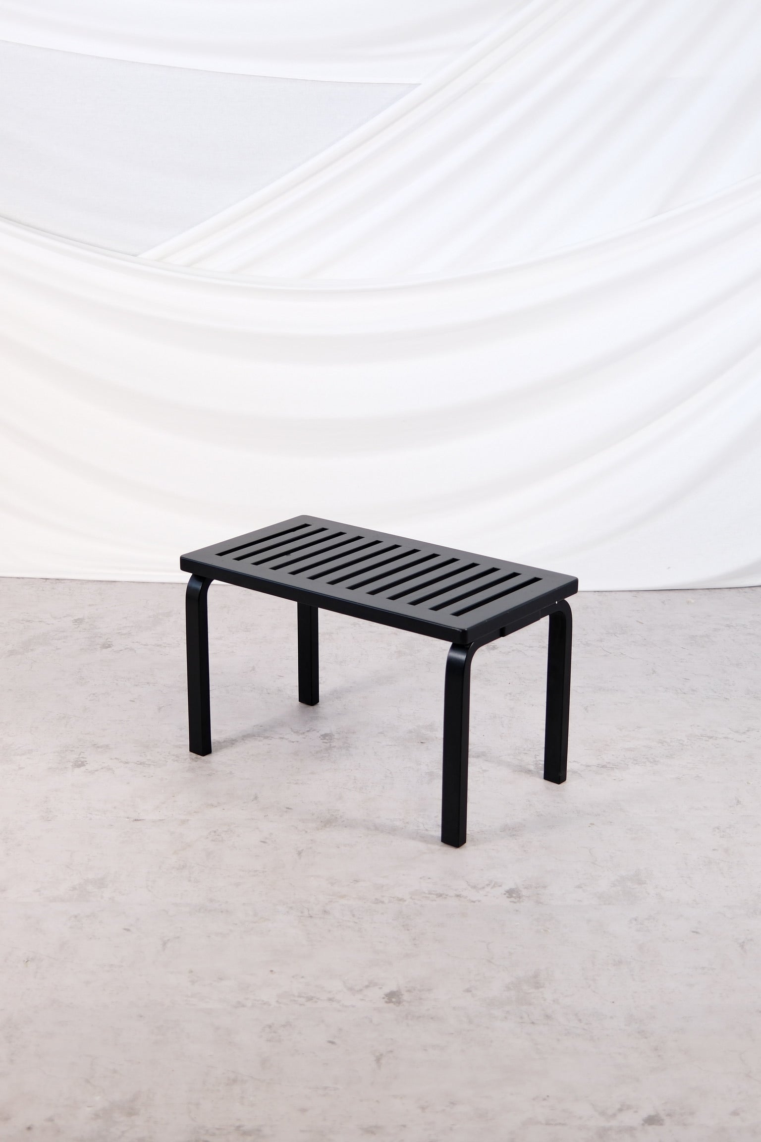 "Artek 153B bench in black, design by Alvar Aalto, photographed in studio setting."