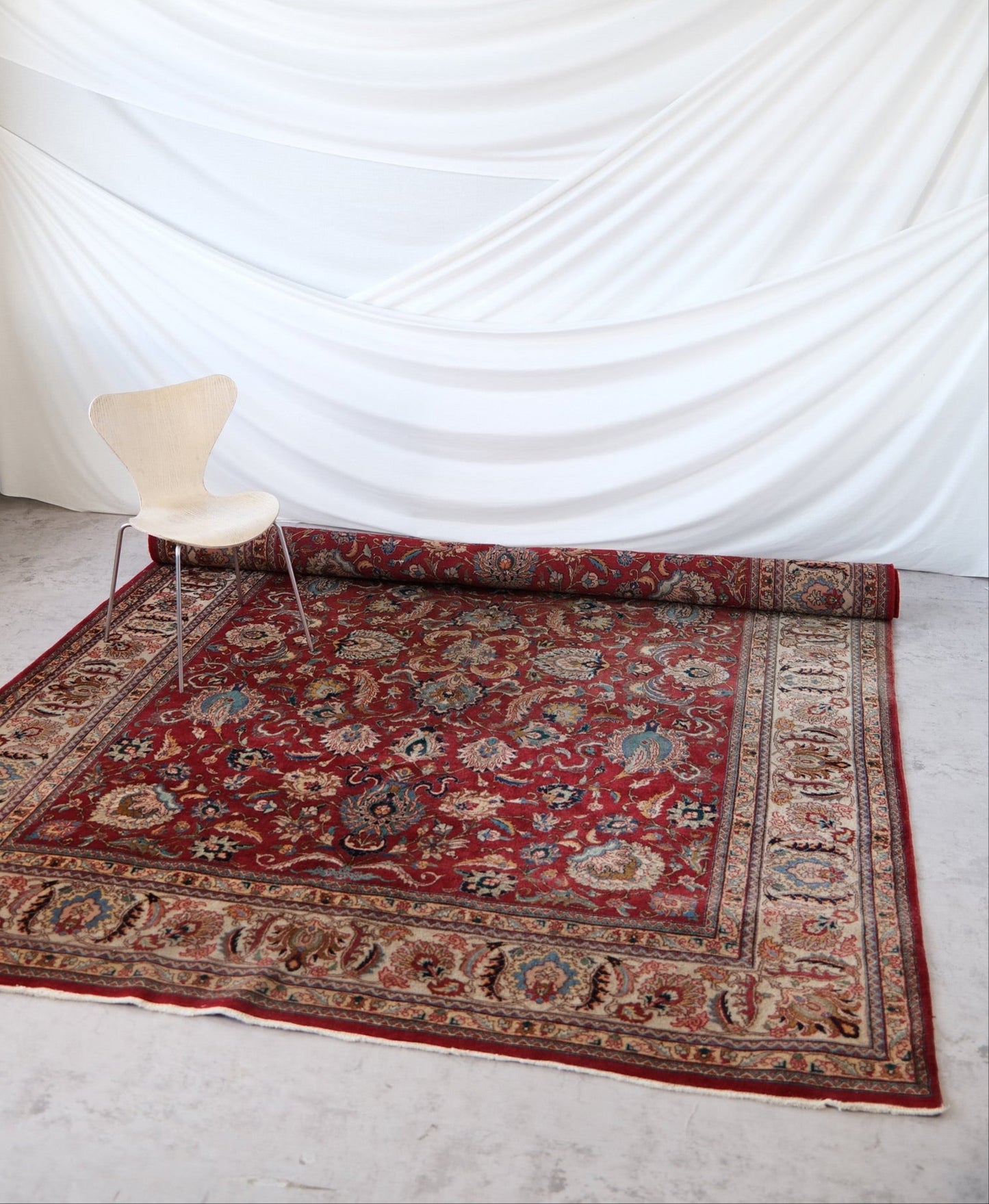 Large hand-knotted Persian rug, 360 × 260 cm. Red field with floral motifs and ornate cream and blue border.