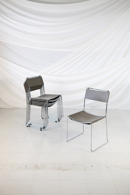 Set of 7 vintage Italian dining chairs with chrome frame and grey leather seat and backrest, stackable design.