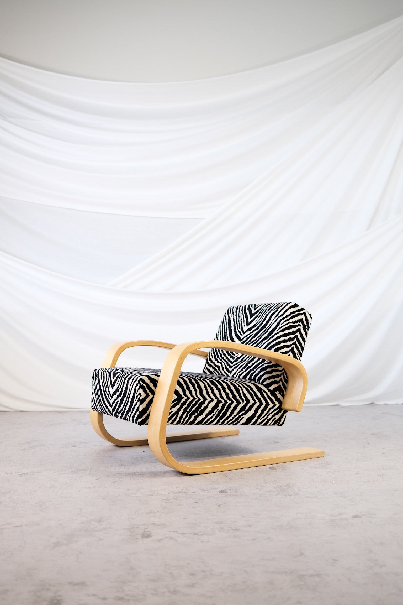 Alvar Aalto 400 Tank chair by Artek with zebra upholstery and curved birch arms.