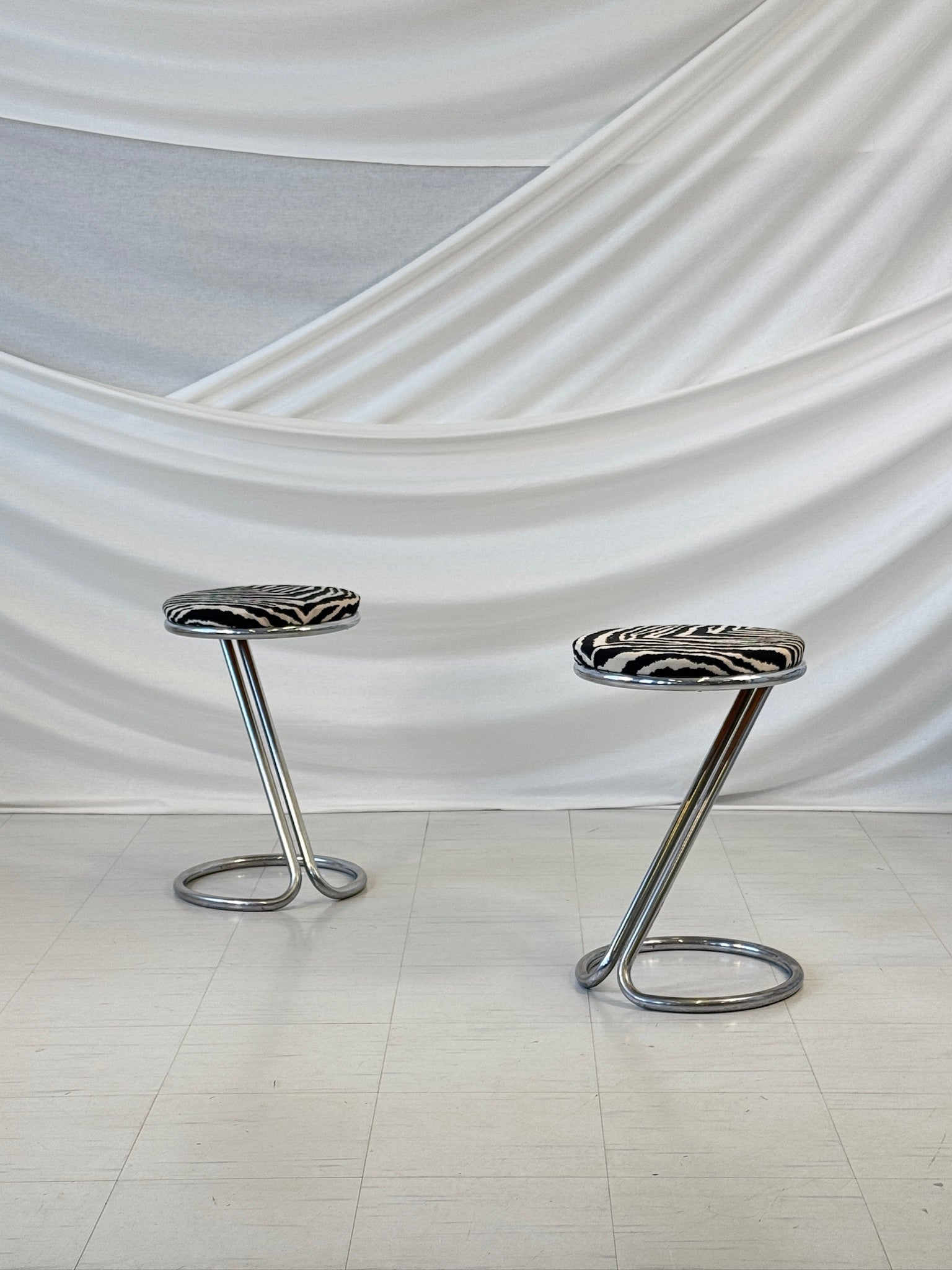 A pair of vintage chrome bar stools with round zebra-patterned upholstered seats, designed in a sculptural Z-shape by Pauli Blomstedt.