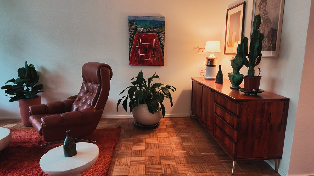 Brown leather armchair, reddish rug, plants and a wooden sideboard in Matti's living room.