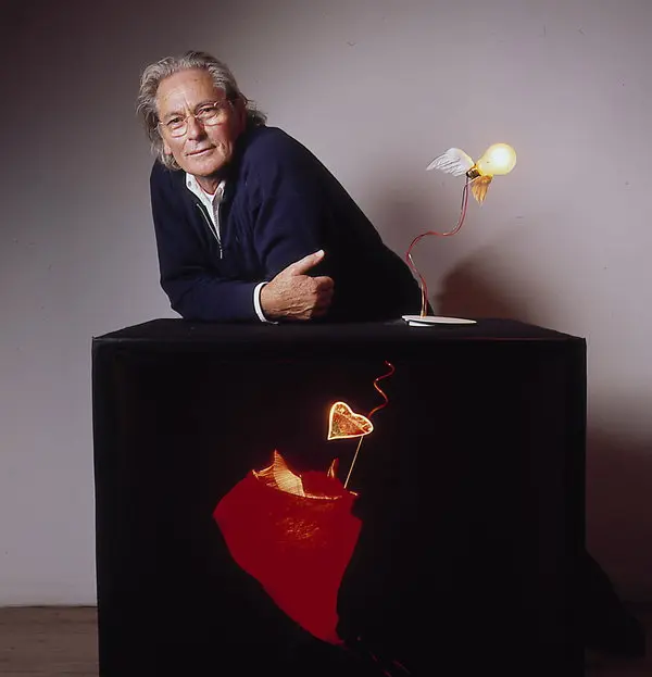 Ingo Maurer beside an illuminated winged bulb lamp