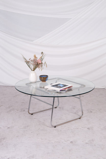 Glass coffee table with metal legs on a light gray floor against a white wall