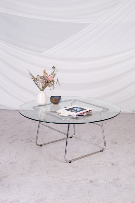Glass coffee table with metal legs on a light gray floor against a white wall