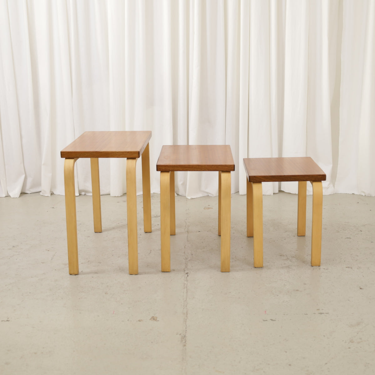 Three wooden nesting tables with brown tops and light bentwood legs, shown side by side