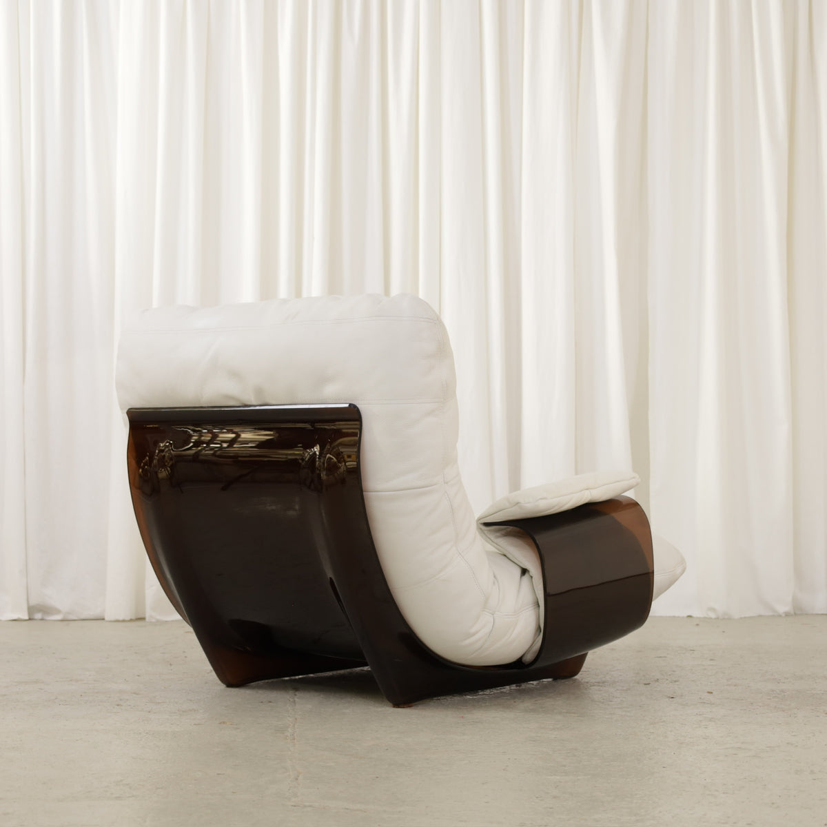 White lounge chair showing rear and side of dark frame