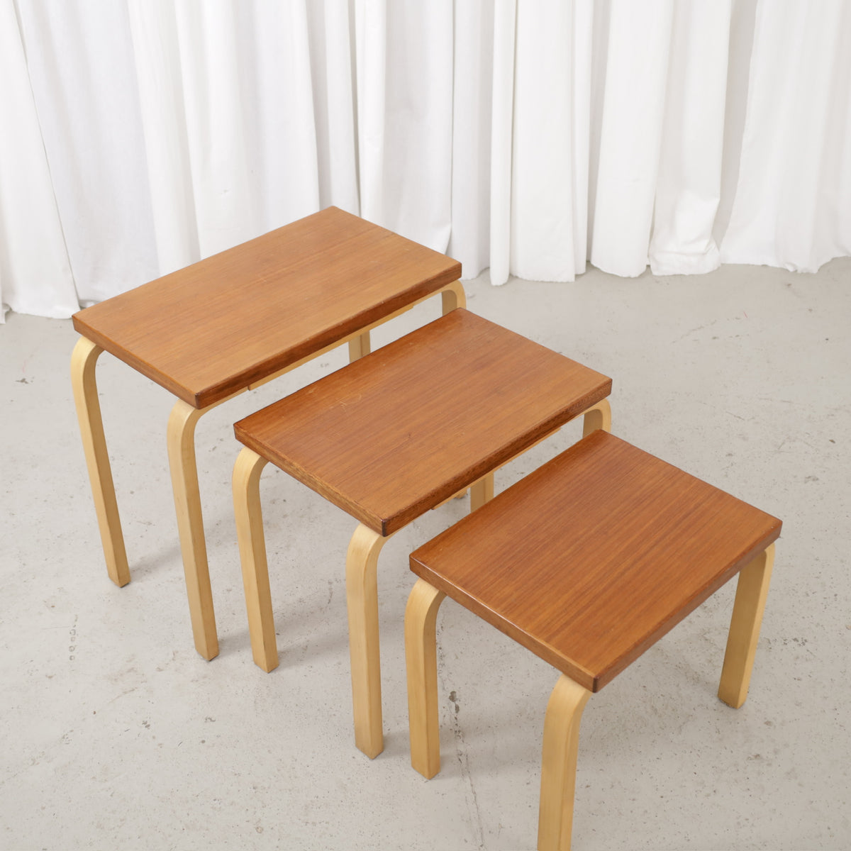 Three nesting tables with brown wooden tops and pale bentwood legs, angled view