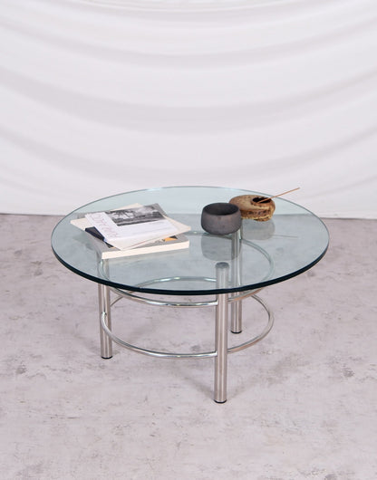 Glass coffee table with metal legs on a light gray floor against a white wall
