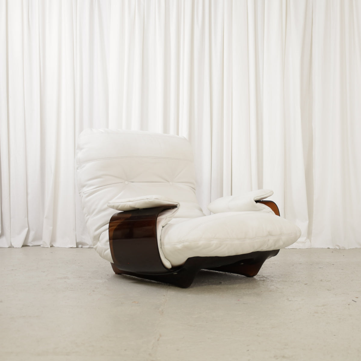 White lounge chair with dark curved frame, front three-quarter view