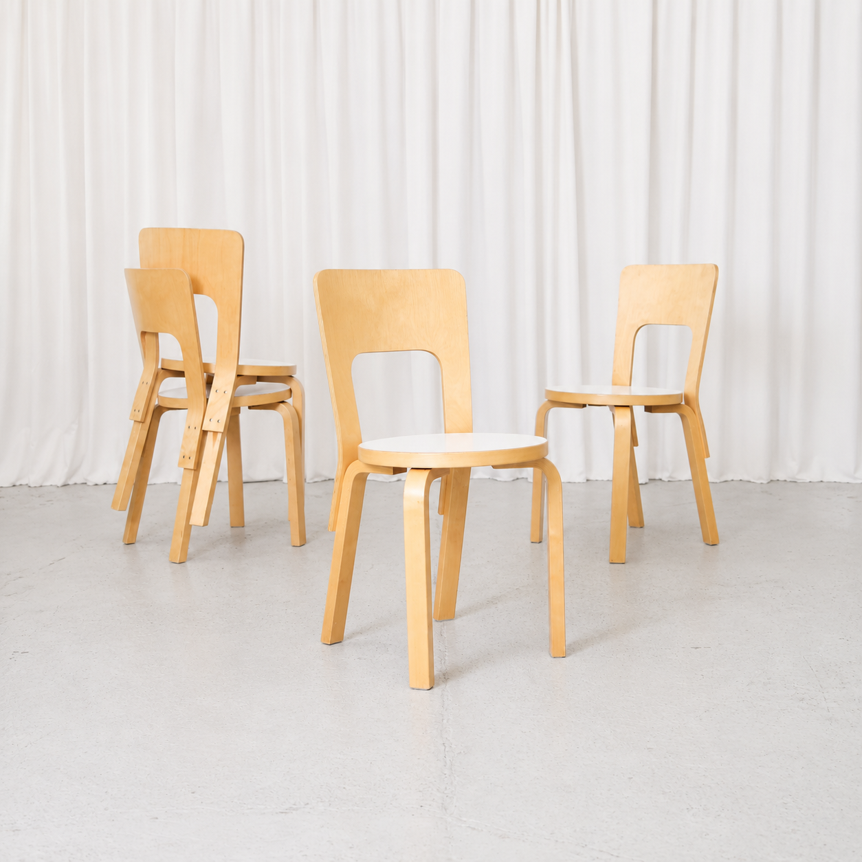 Vintage Alvar Aalto Artek 66 chairs with natural birch frames and white laminate seats. A classic Finnish design with timeless, practical proportions.