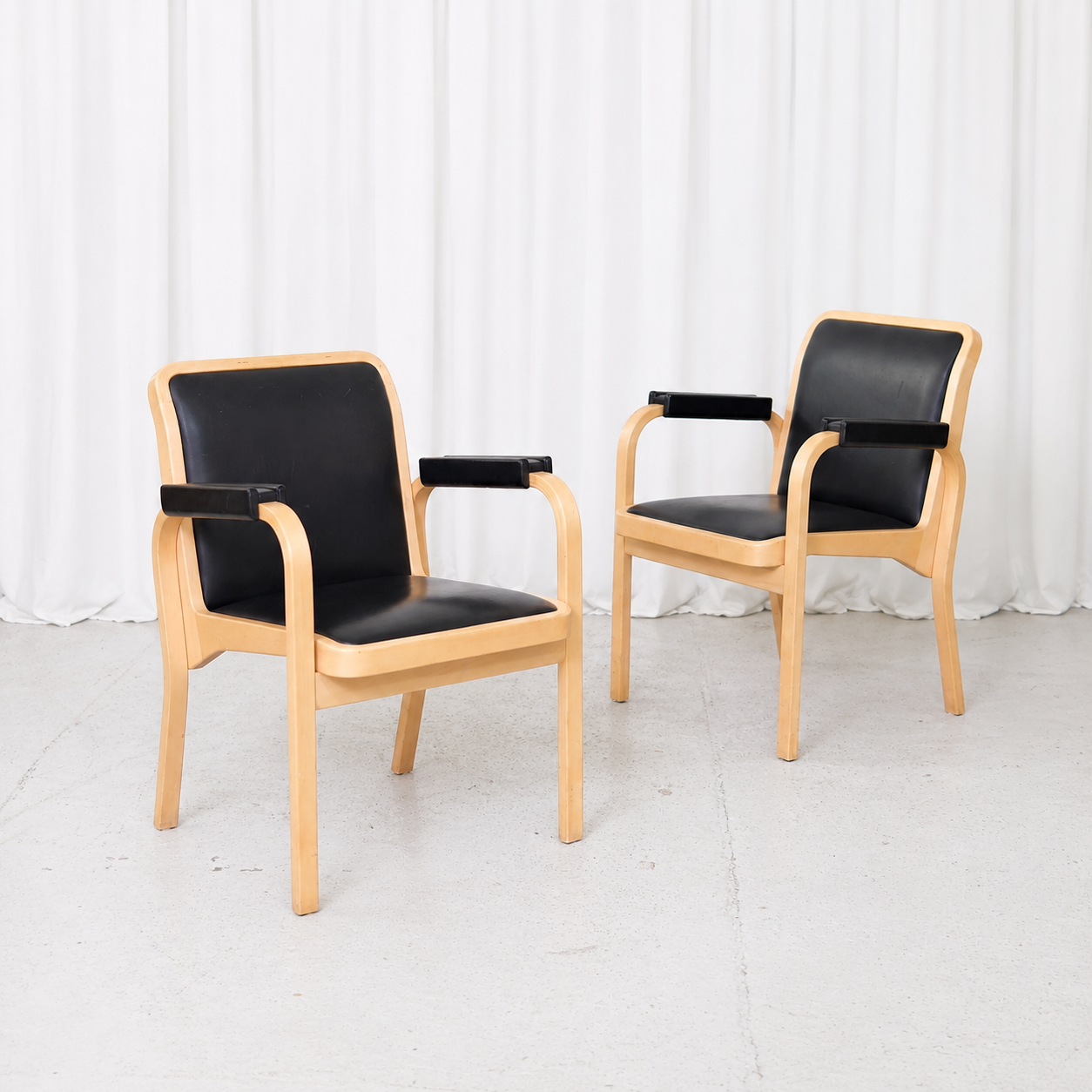 Vintage E45 armchair designed by Alvar Aalto for Artek in lacquered birch and black leather, featuring distinctive leather-padded armrests.