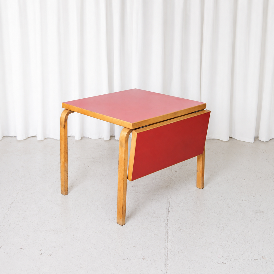 Vintage Artek DL81C drop-leaf table by Alvar Aalto with red linoleum top and birch frame. Practical Finnish design with beautiful age-related patina.