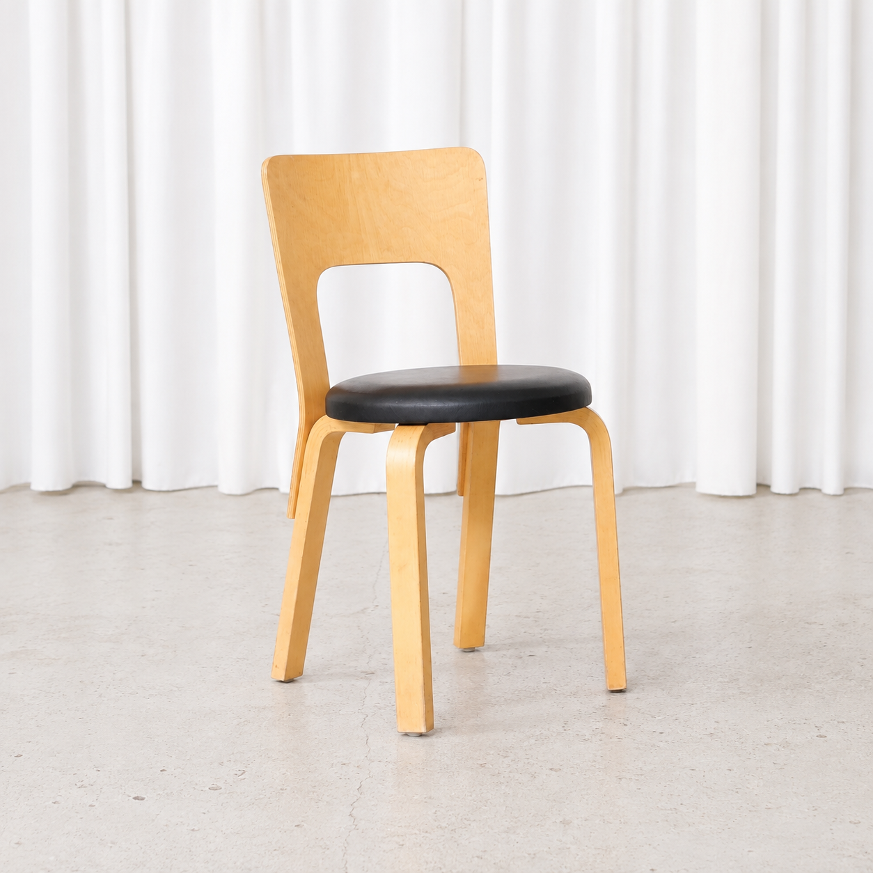 Vintage Artek Chair 66 designed by Alvar Aalto, featuring a natural birch frame and black leather upholstered seat. Good condition with natural patina.