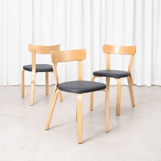 Vintage Artek Chair 69 designed by Alvar Aalto, featuring a birch frame and dark grey upholstery. A versatile classic of Finnish modernist design.