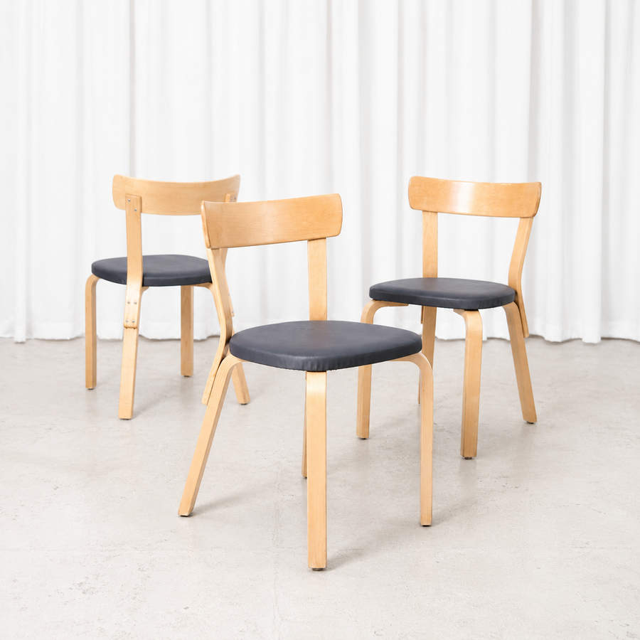 Vintage Artek Chair 69 designed by Alvar Aalto, featuring a birch frame and dark grey upholstery. A versatile classic of Finnish modernist design.