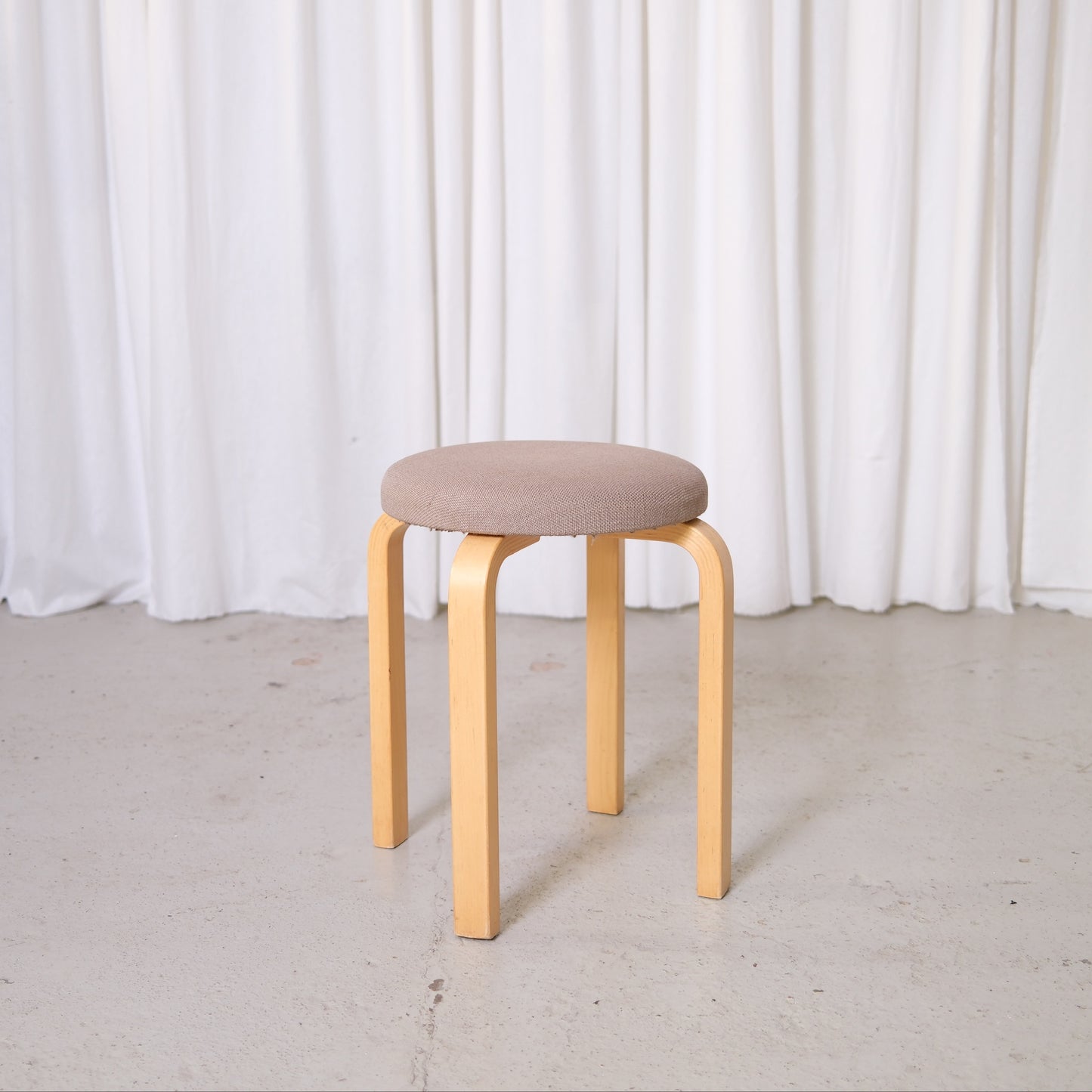Vintage Artek E60 stool by Alvar Aalto with birch legs and Artek fabric upholstered round seat.