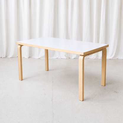 Vintage Artek Model 81A table by Alvar Aalto with a white laminate top and natural birch L-legs. Good condition with minor edge wear.