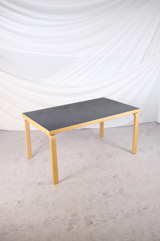 Artek 82A dining table with black linoleum top and birch frame by Alvar Aalto
Side view of Artek 82A table, black linoleum top, Finnish design classic
Detail of birch legs and black linoleum tabletop on Alvar Aalto’s 82A table
Vintage Artek 82A table in black linoleum and birch, Scandinavian design
Finnish modernist table by Alvar Aalto, Artek 82A model with black linoleum