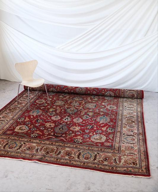 Large hand-knotted Persian rug, 360 × 260 cm. Red field with floral motifs and ornate cream and blue border.
