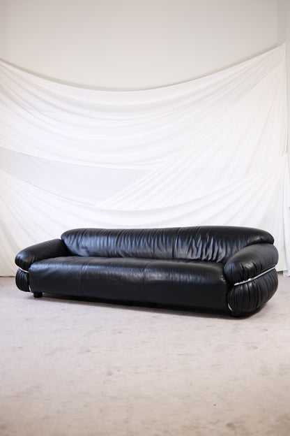 Black leather Gianfranco Frattini Sesann sofa for Cassina with chrome frame, photographed in soft natural light against a white draped backdrop.