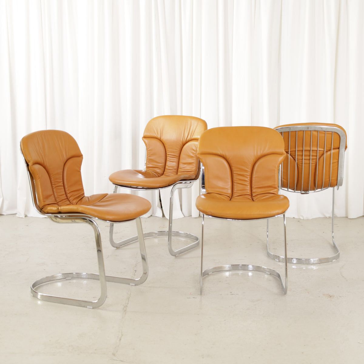 Cidue dining chairs in cognac leather with polished chrome cantilever frames and detailed padded backs
