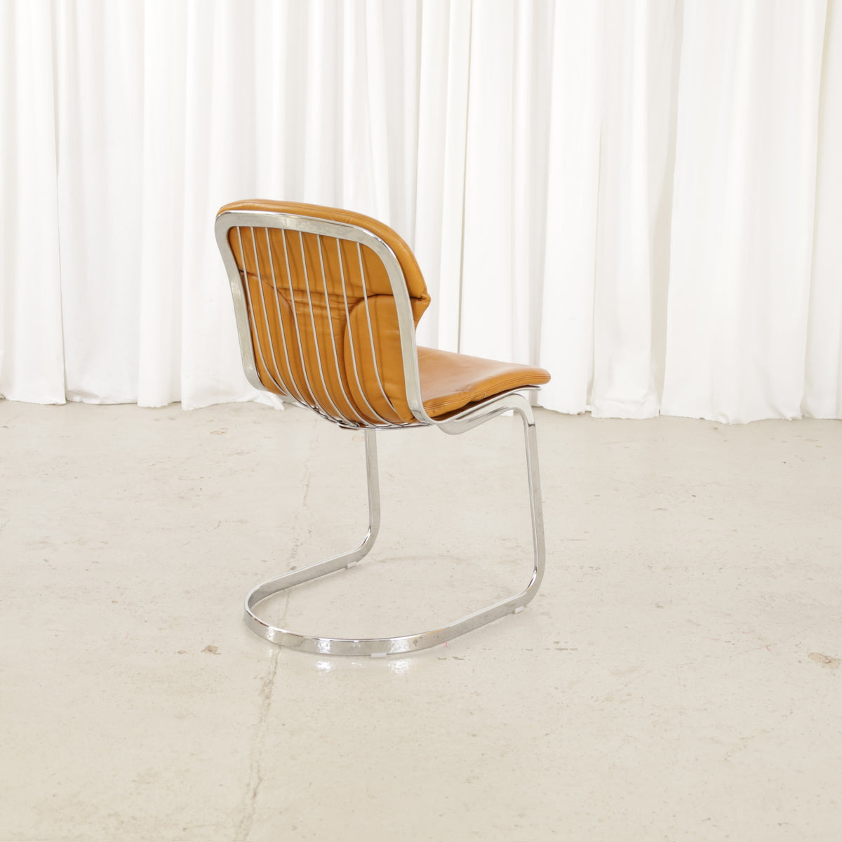 Cidue dining chairs in cognac leather with polished chrome cantilever frames and detailed padded backs