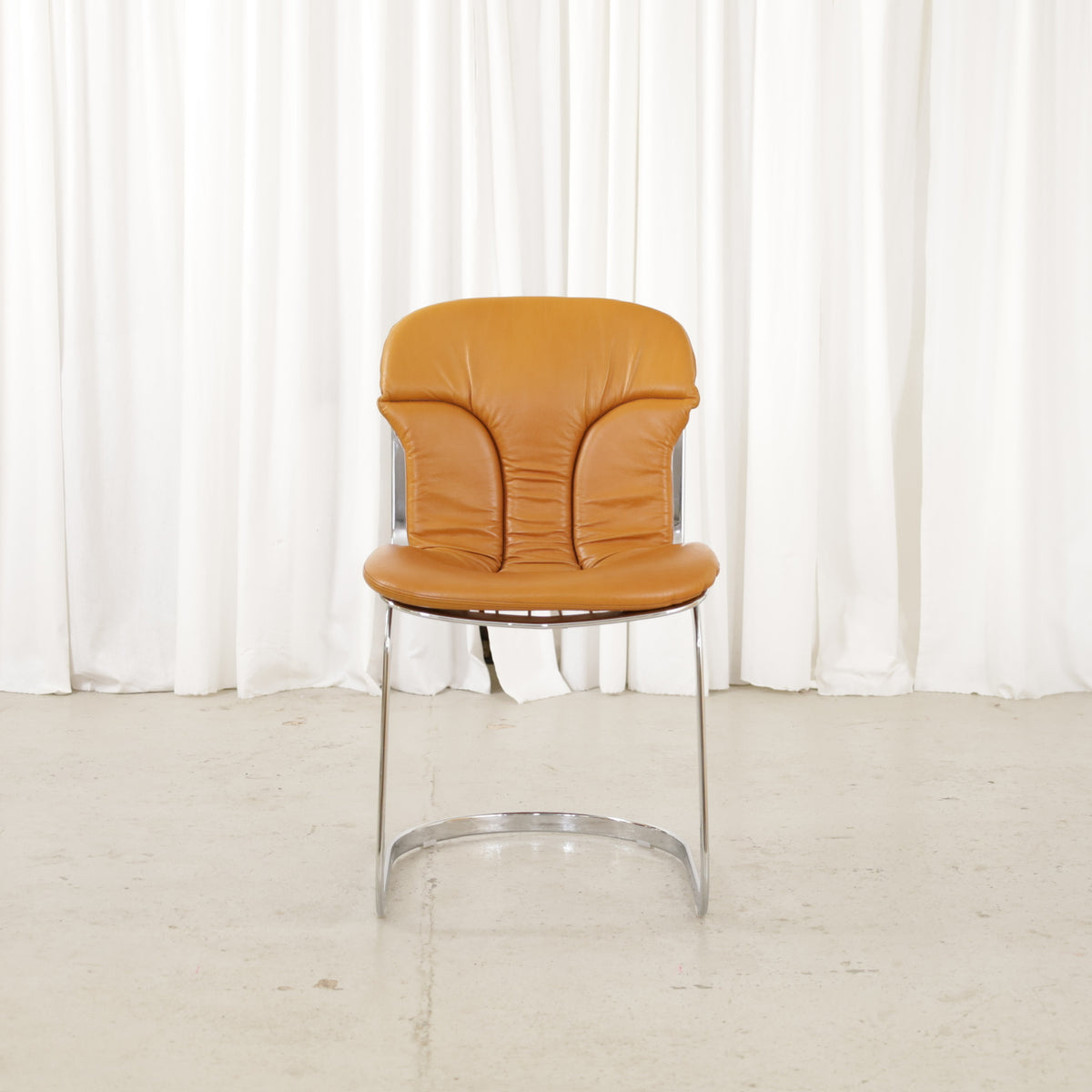 Cidue dining chairs in cognac leather with polished chrome cantilever frames and detailed padded backs