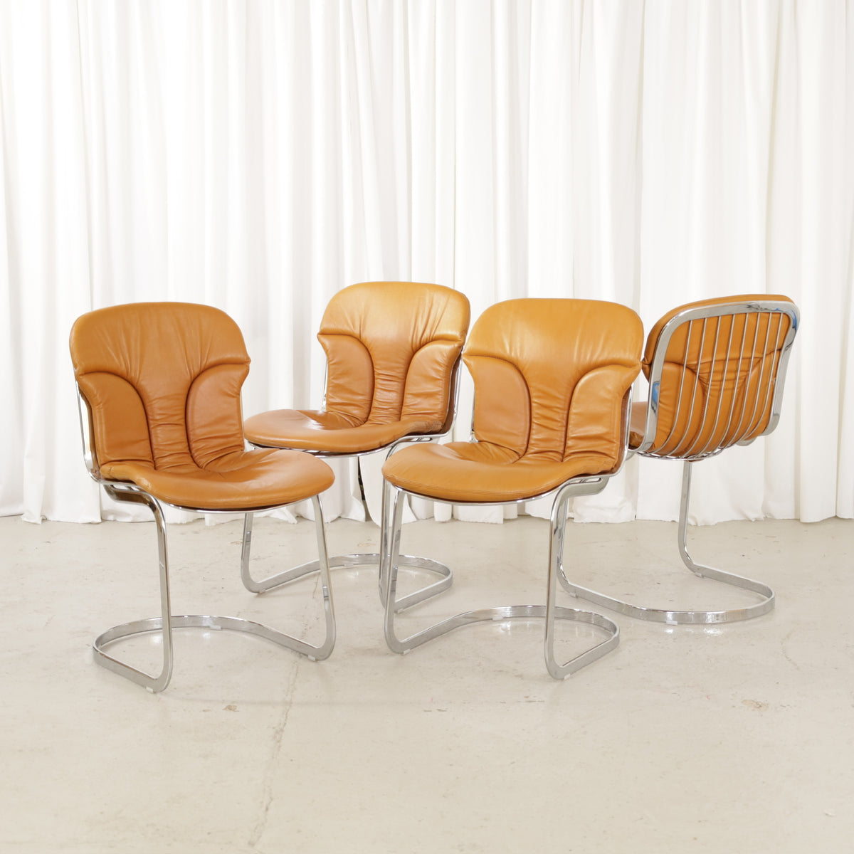 Cidue dining chairs in cognac leather with polished chrome cantilever frames and detailed padded backs