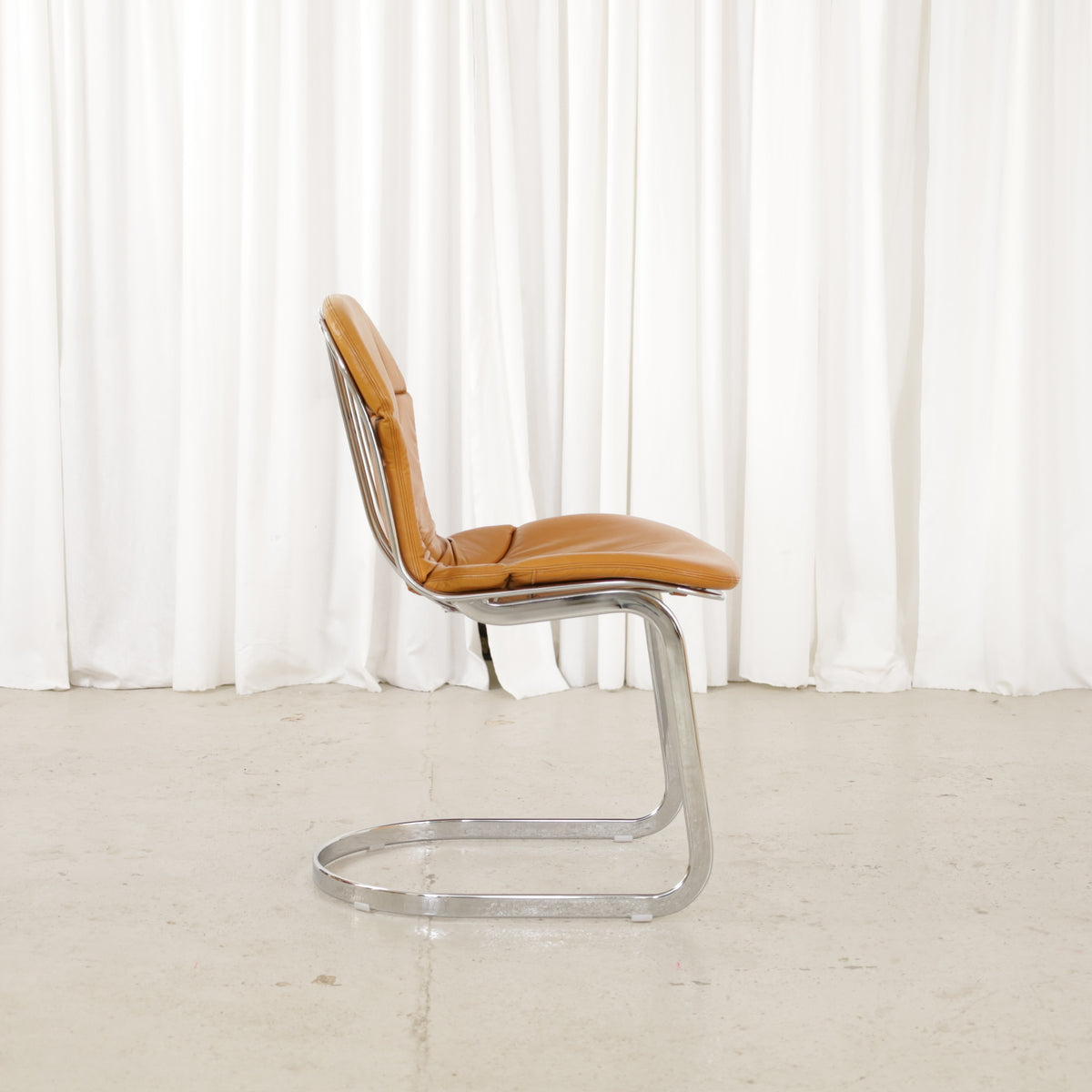 Cidue dining chairs in cognac leather with polished chrome cantilever frames and detailed padded backs