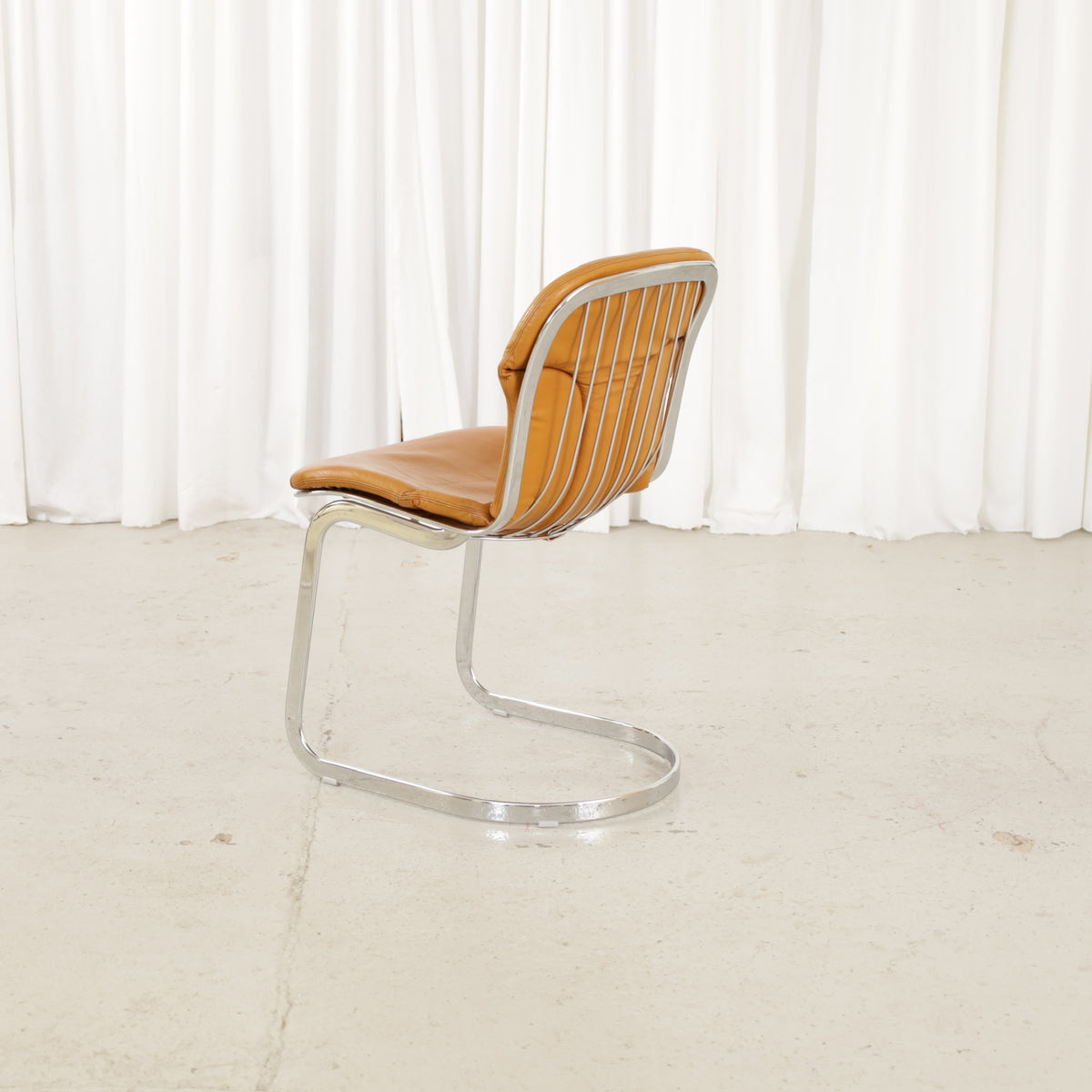 Cidue dining chairs in cognac leather with polished chrome cantilever frames and detailed padded backs