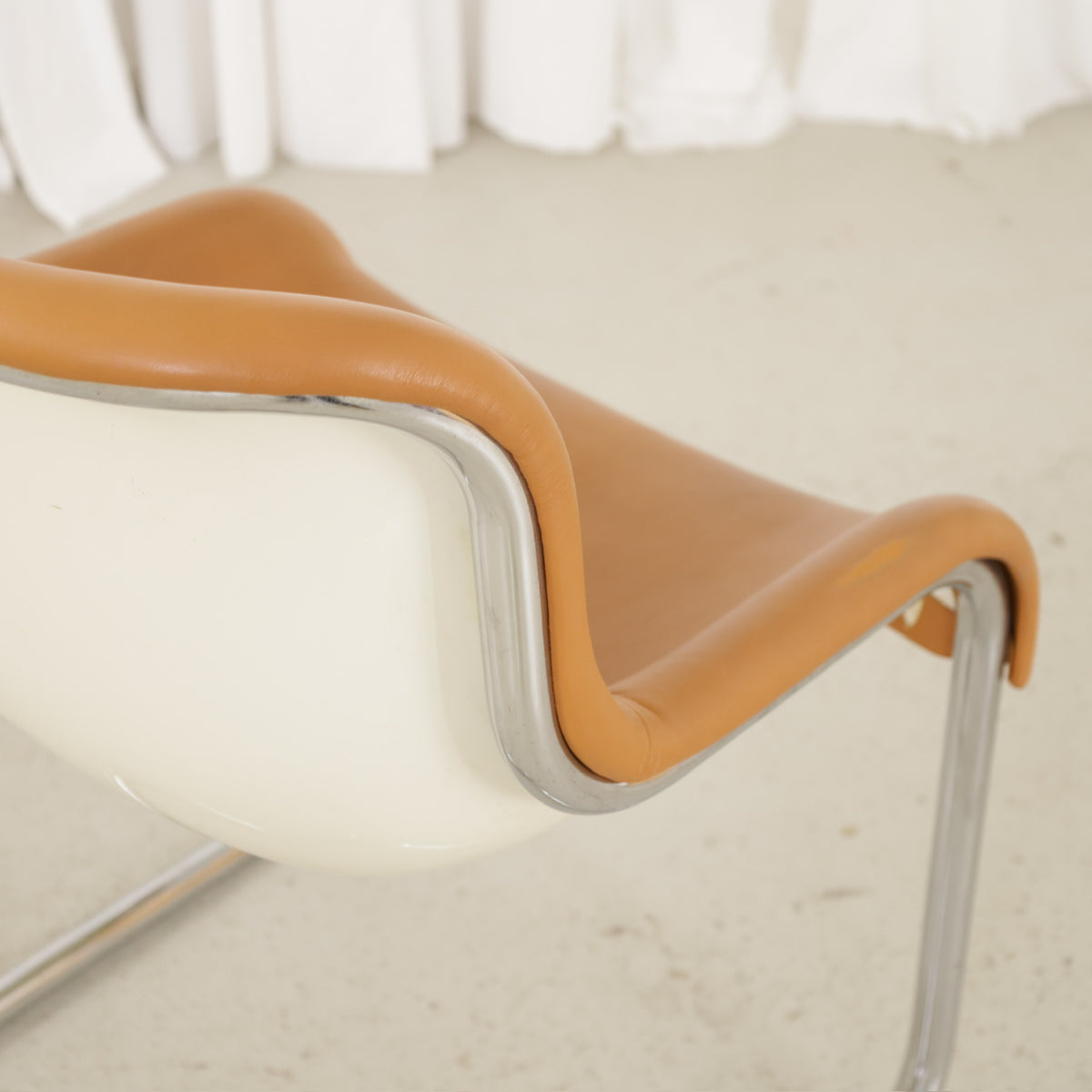 Leather upholstery edge and cream plastic shell of an Elefantti chair