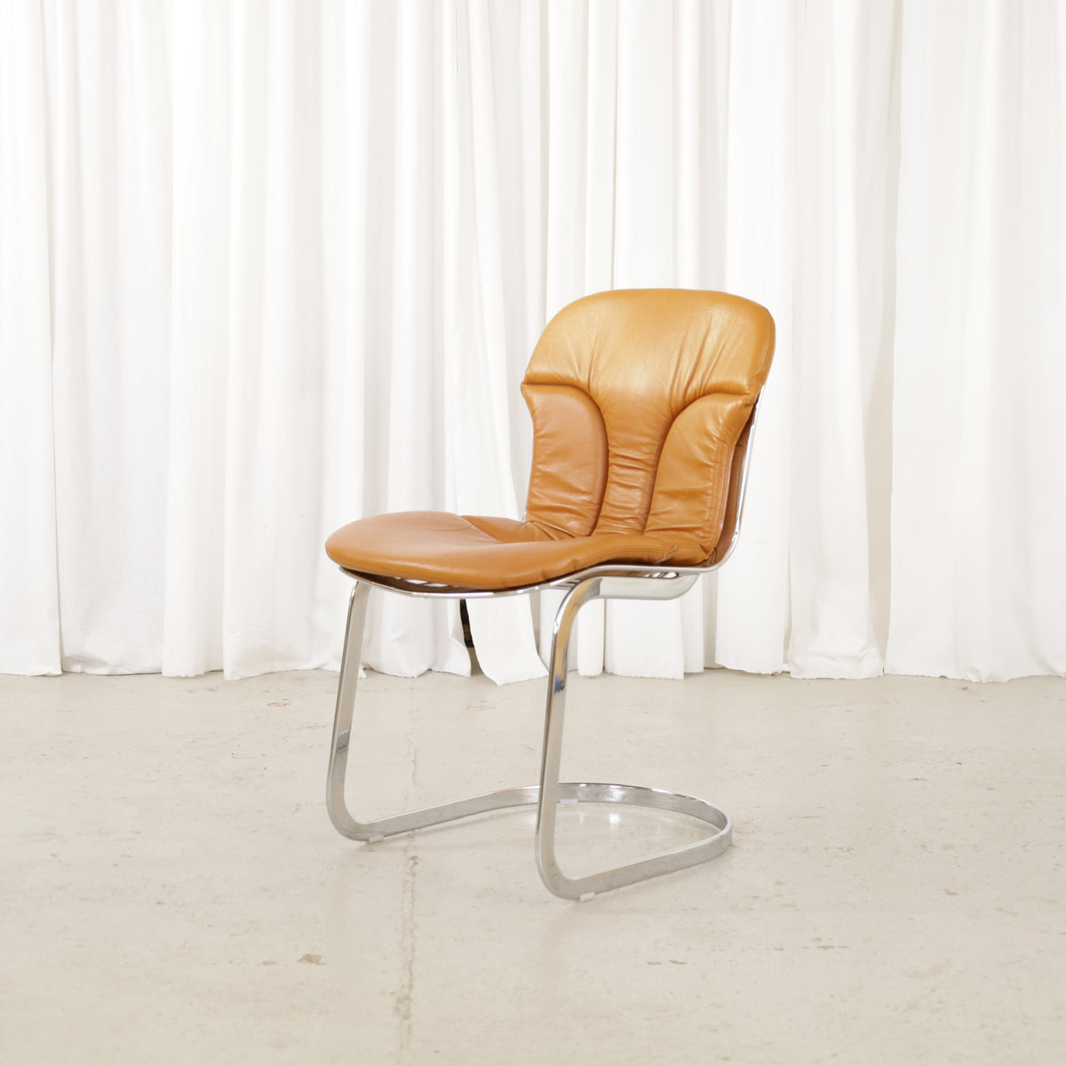 Cidue dining chairs in cognac leather with polished chrome cantilever frames and detailed padded backs