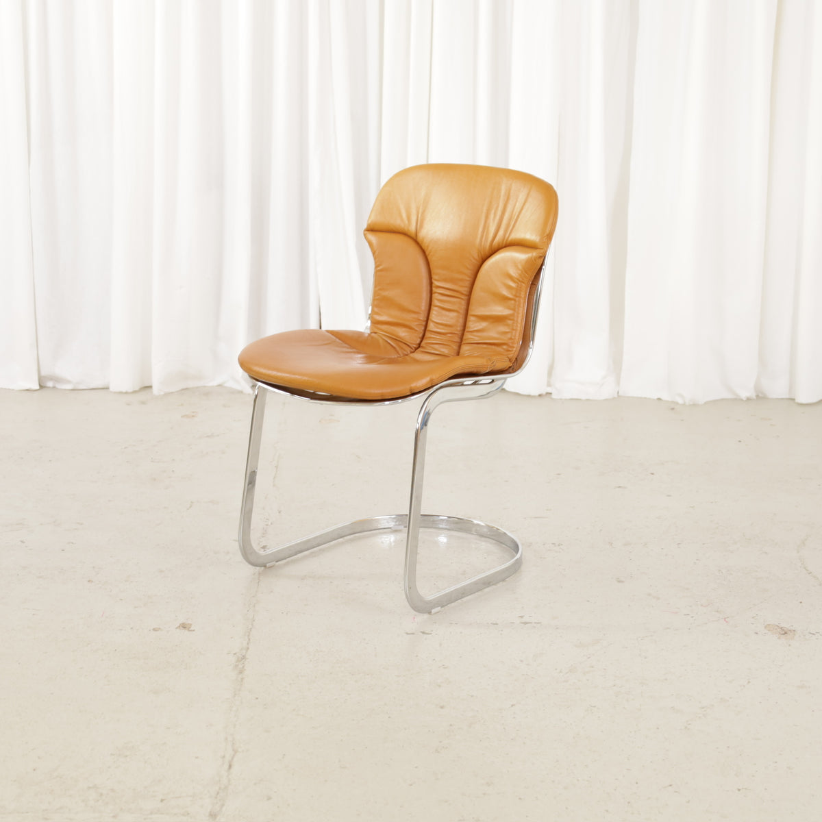Cidue dining chairs in cognac leather with polished chrome cantilever frames and detailed padded backs