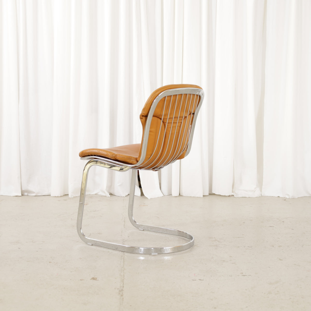 Cidue dining chairs in cognac leather with polished chrome cantilever frames and detailed padded backs