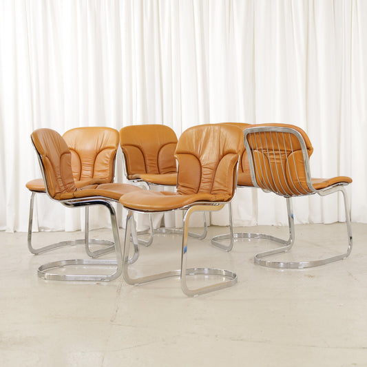 Cidue dining chairs in cognac leather with polished chrome cantilever frames and detailed padded backs