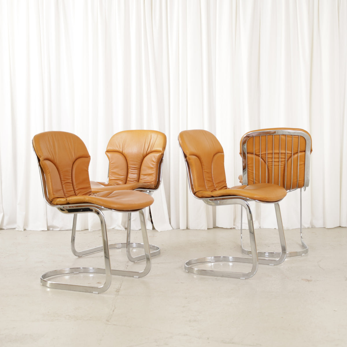 Cidue dining chairs in cognac leather with polished chrome cantilever frames and detailed padded backs