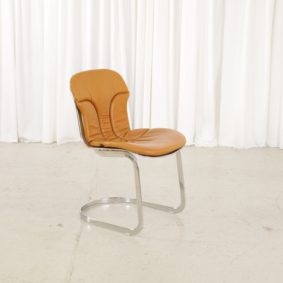Cidue dining chairs in cognac leather with polished chrome cantilever frames and detailed padded backs
