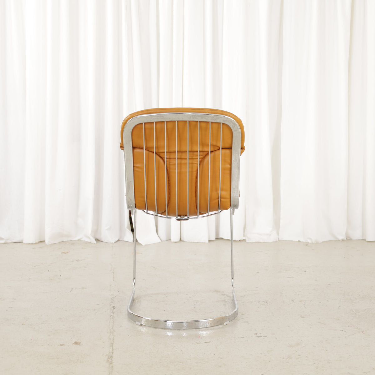 Cidue dining chairs in cognac leather with polished chrome cantilever frames and detailed padded backs