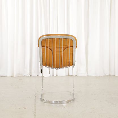 Cidue dining chairs in cognac leather with polished chrome cantilever frames and detailed padded backs