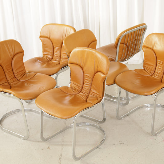 Cidue dining chairs in cognac leather with polished chrome cantilever frames and detailed padded backs