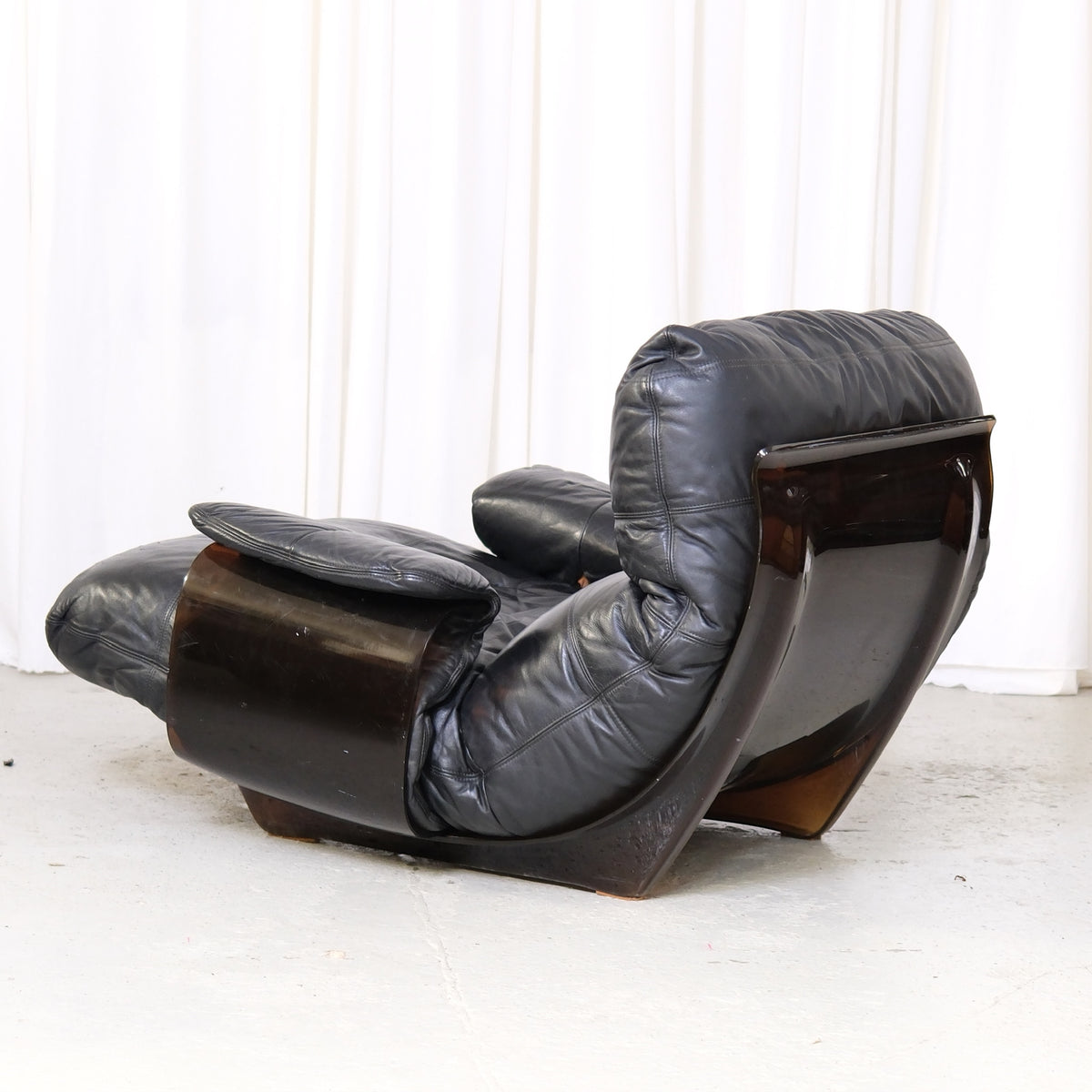 Detail of curved smoked acrylic shell and leather upholstery