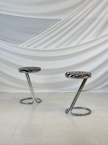 A pair of vintage chrome bar stools with round zebra-patterned upholstered seats, designed in a sculptural Z-shape by Pauli Blomstedt.