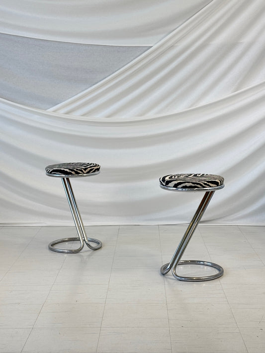 A pair of vintage chrome bar stools with round zebra-patterned upholstered seats, designed in a sculptural Z-shape by Pauli Blomstedt.