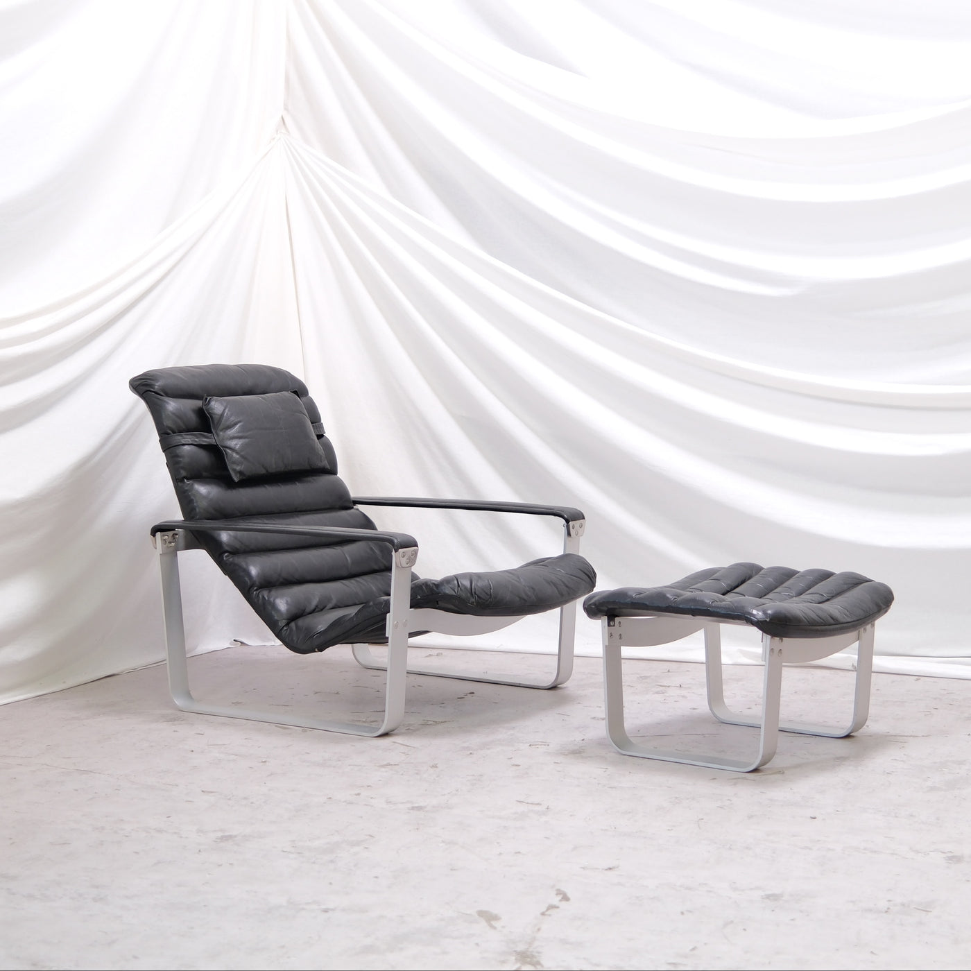Ilmari Lappalainen Pulkka lounge chair with matching ottoman by Asko Export. Black leather and aluminium frame, adjustable seat. Finnish design classic. Worldwide shipping available.