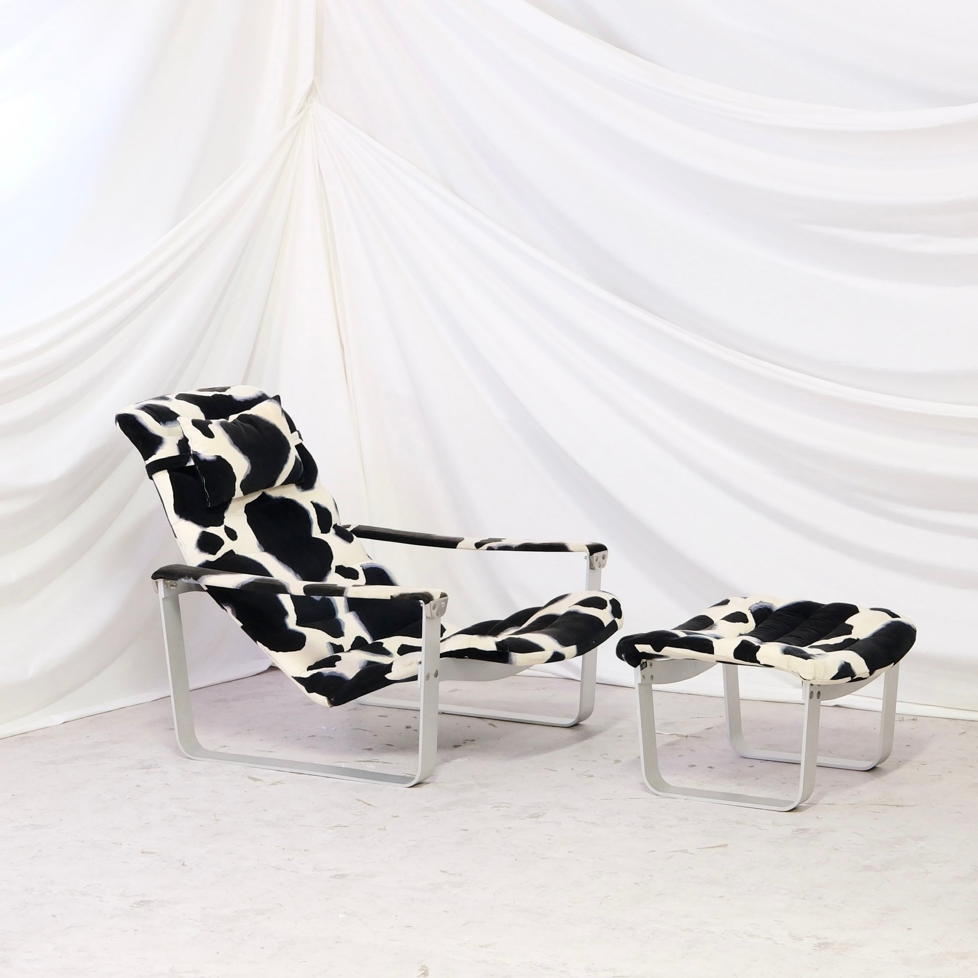 Vintage Ilmari Lappalainen Pulkka lounge chair with matching ottoman for Asko. Cowhide print canvas upholstery with white metal frame. Finnish design classic.