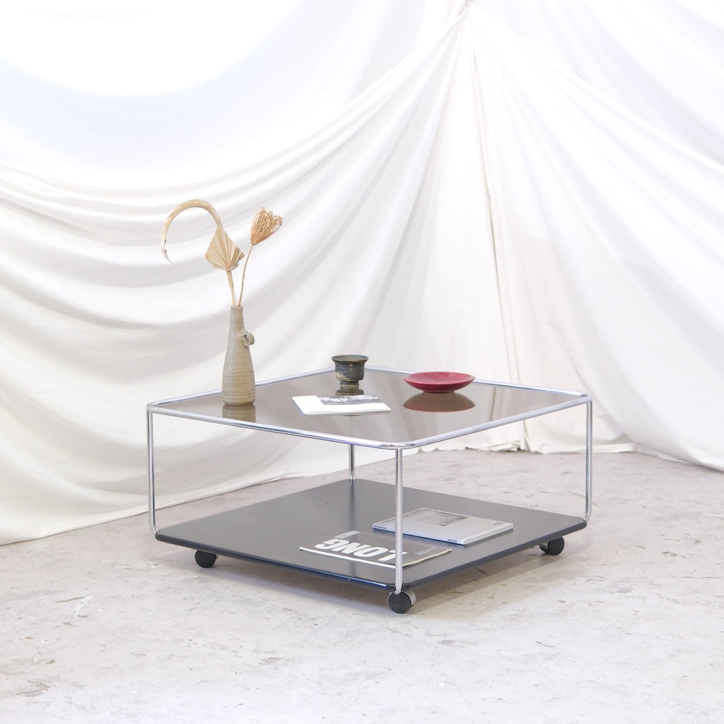 Vintage Hannibal coffee table designed by Kurt Hvistjö for Isku. Chrome frame with wheels, smoked glass top and black lacquered lower shelf.