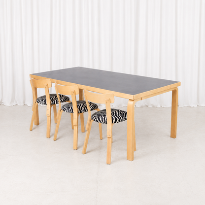 Vintage Artek Table 83 by Alvar Aalto with a black linoleum top and natural birch L-legs. A spacious Finnish dining table measuring 182 × 91 cm.