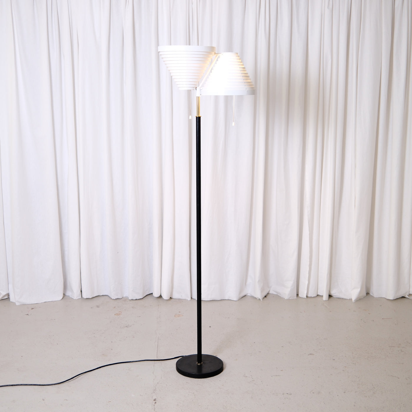 Rare Alvar Aalto A809 floor lamp manufactured by Valaisinpaja. Collectible Finnish modern lighting design with layered white metal shades and brass details.
